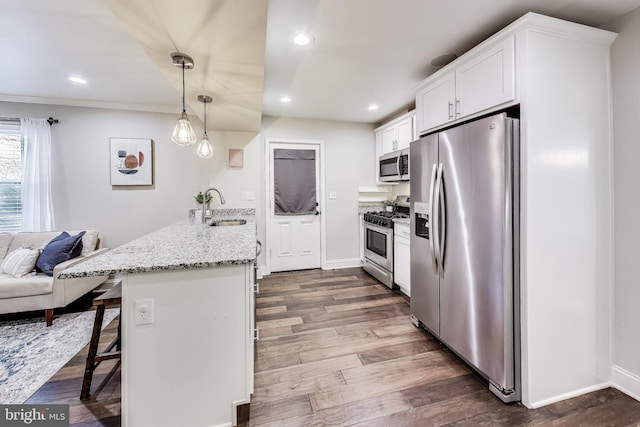 kitchen featuring sink, a breakfast bar area, decorative light fixtures, white cabinetry, and stainless steel appliances