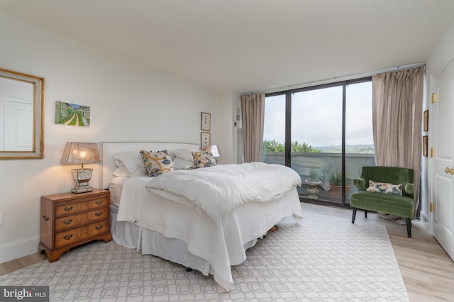 bedroom with access to outside, expansive windows, and light hardwood / wood-style floors