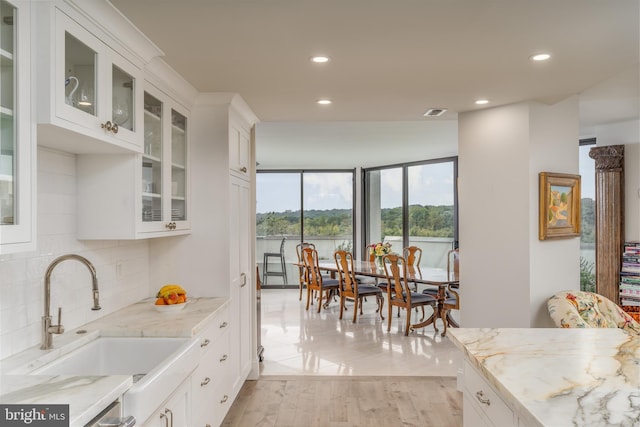 kitchen with white cabinets, light stone counters, and sink