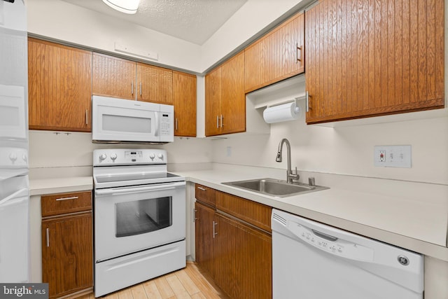 kitchen featuring a textured ceiling, light hardwood / wood-style floors, white appliances, and sink