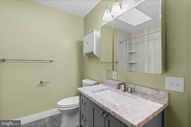 bathroom with hardwood / wood-style floors, vanity, toilet, and a skylight