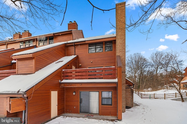 snow covered back of property with a balcony