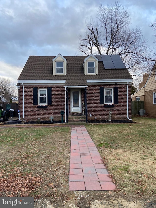 view of front of property featuring solar panels, cooling unit, and a front yard