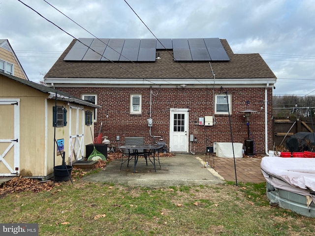 rear view of property featuring a yard, a patio area, and solar panels