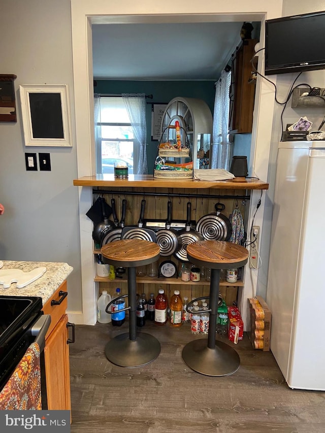 bar featuring hardwood / wood-style flooring, white refrigerator, and black electric range oven