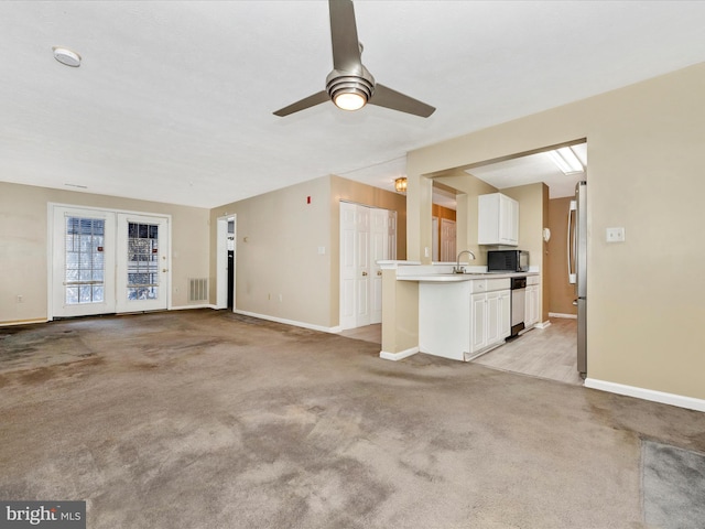 unfurnished living room with sink, light colored carpet, and ceiling fan