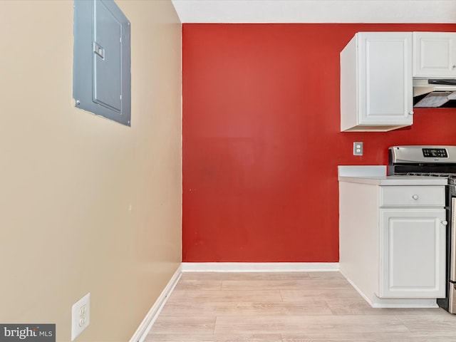 kitchen featuring white cabinetry, stainless steel gas range, light wood-type flooring, and electric panel