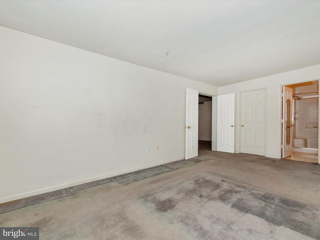 unfurnished bedroom featuring ensuite bathroom and carpet floors