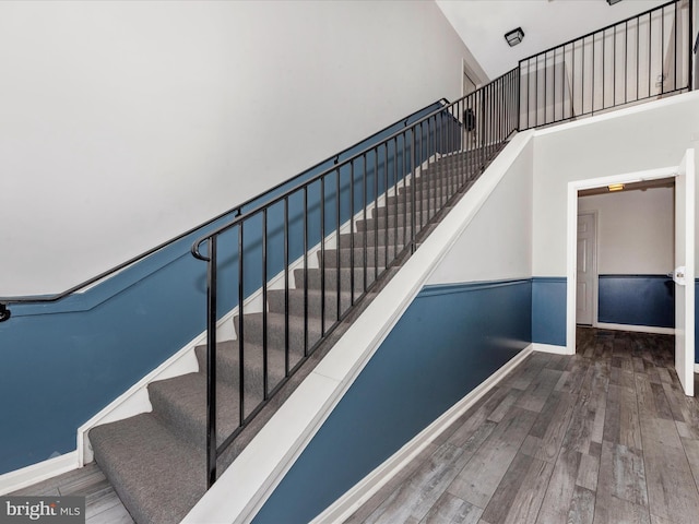 stairway with hardwood / wood-style flooring and a towering ceiling