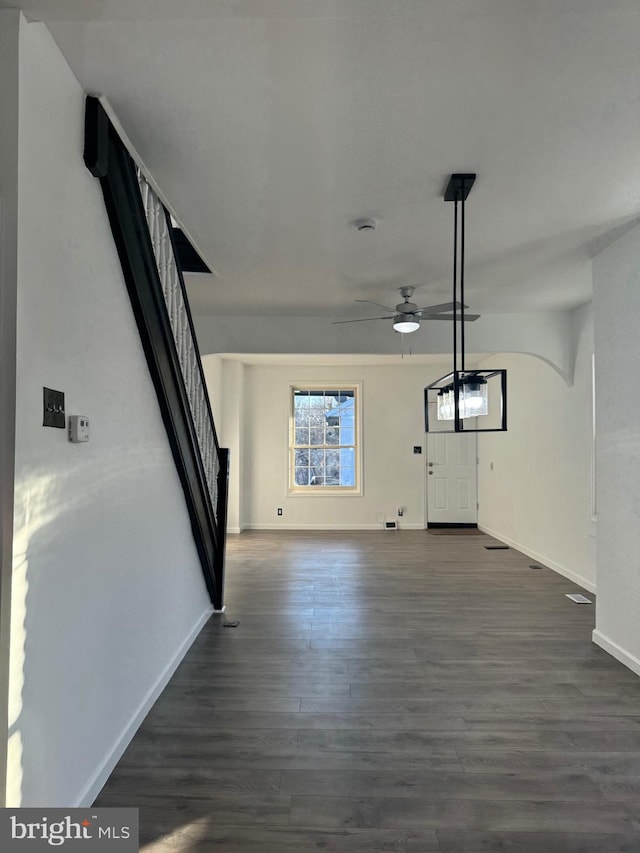 unfurnished living room featuring dark wood-type flooring and ceiling fan