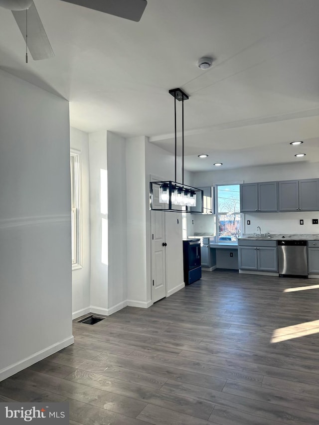 kitchen featuring stainless steel dishwasher, pendant lighting, dark hardwood / wood-style flooring, sink, and gray cabinets