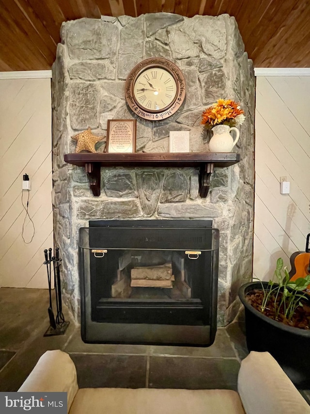 details with wood walls, a stone fireplace, wooden ceiling, and ornamental molding