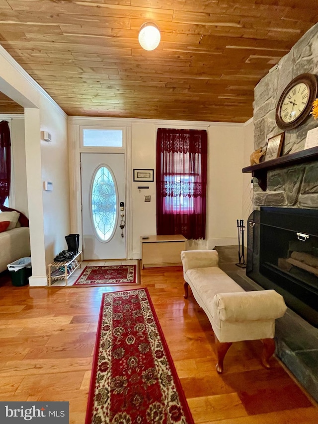 foyer entrance with hardwood / wood-style floors, wooden ceiling, and ornamental molding