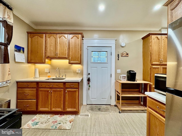 kitchen with black electric range oven, stainless steel fridge, crown molding, and sink