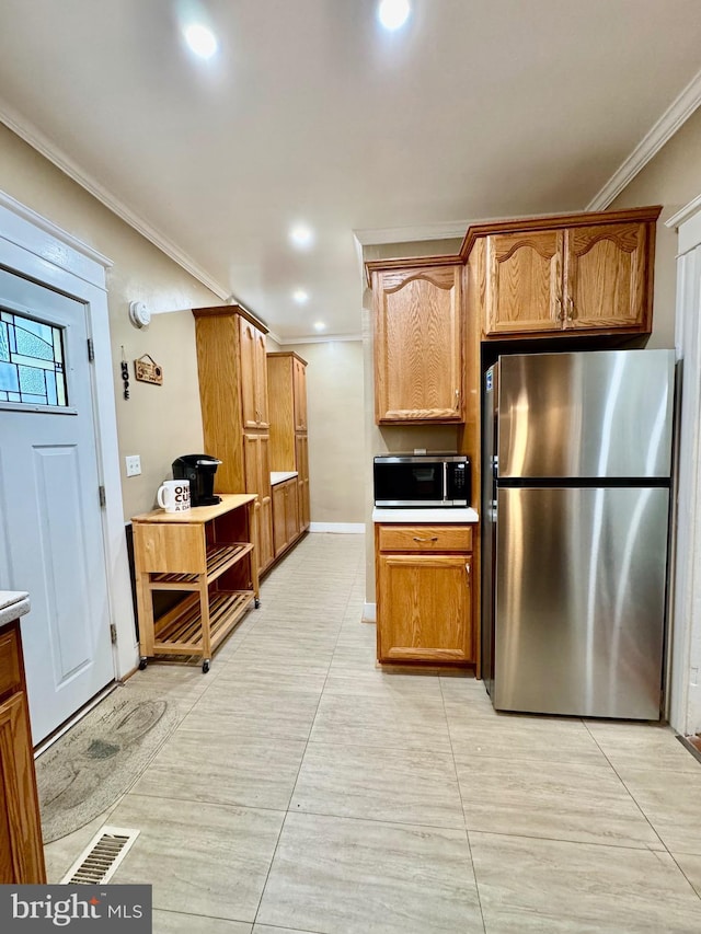 kitchen with stainless steel appliances, ornamental molding, and light tile patterned flooring