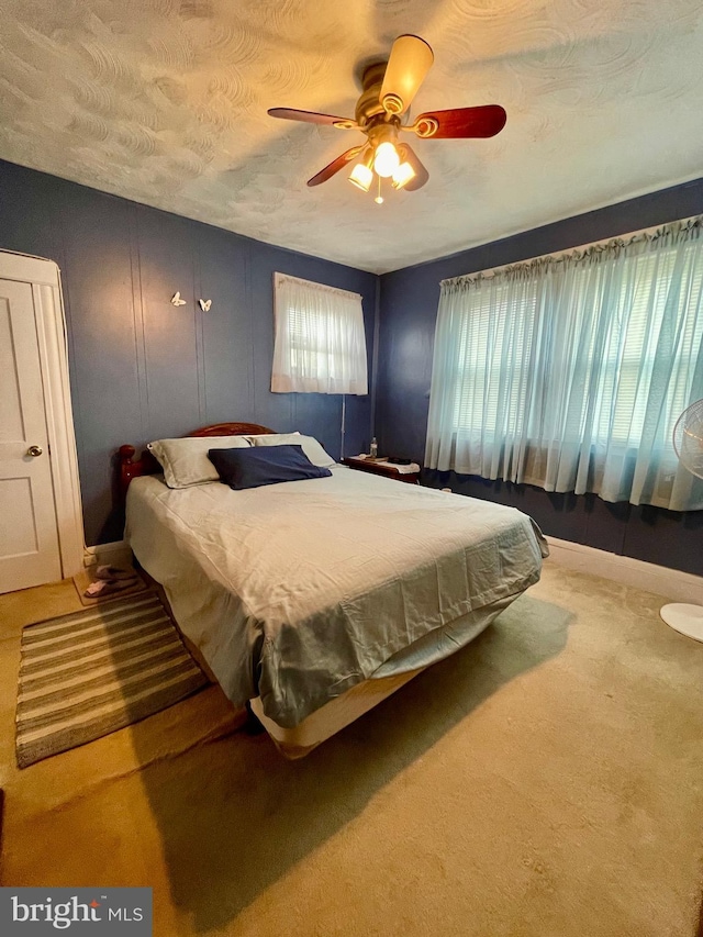 carpeted bedroom featuring ceiling fan and a textured ceiling