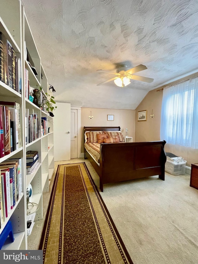 unfurnished bedroom featuring ceiling fan, carpet floors, a textured ceiling, and vaulted ceiling