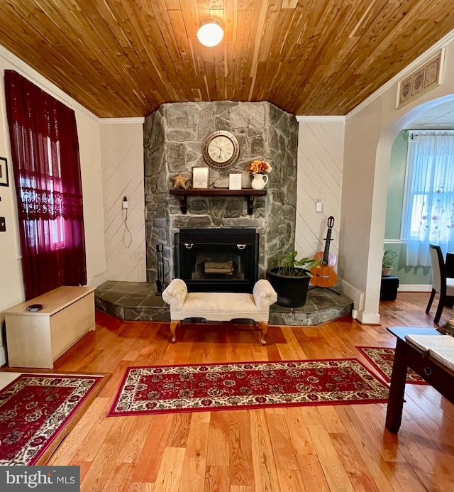 living room featuring wooden ceiling, wood walls, hardwood / wood-style flooring, a fireplace, and ornamental molding