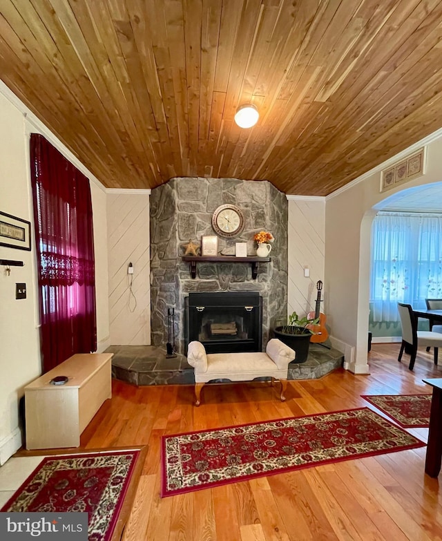 living room featuring ornamental molding, wood ceiling, a fireplace, hardwood / wood-style floors, and wood walls