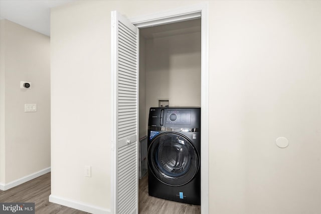 laundry area with washer / dryer and light wood-type flooring