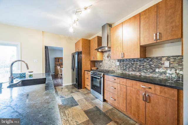 kitchen featuring backsplash, wall chimney range hood, black fridge, sink, and stainless steel gas range