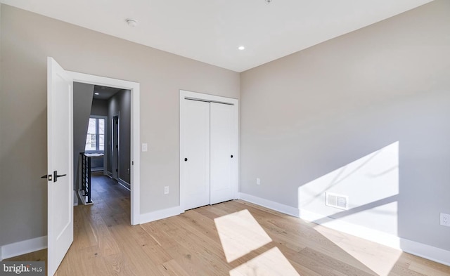 unfurnished bedroom featuring light hardwood / wood-style floors and a closet