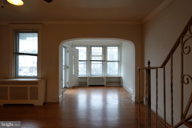 foyer entrance with hardwood / wood-style floors, ornamental molding, and radiator