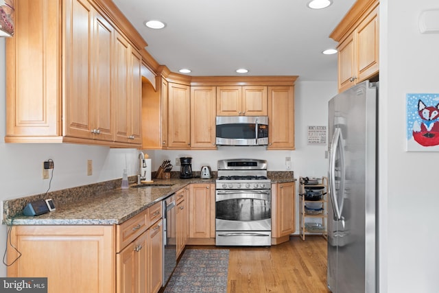 kitchen with sink, light brown cabinets, stainless steel appliances, dark stone countertops, and light wood-type flooring