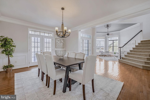 dining space featuring french doors, ceiling fan with notable chandelier, hardwood / wood-style flooring, and ornamental molding