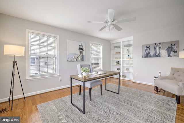 office space with built in shelves, ceiling fan, and wood-type flooring