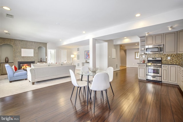 dining area with a tiled fireplace and dark wood-type flooring