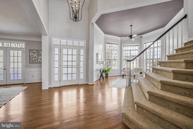 entryway featuring hardwood / wood-style flooring, ceiling fan with notable chandelier, a healthy amount of sunlight, and crown molding