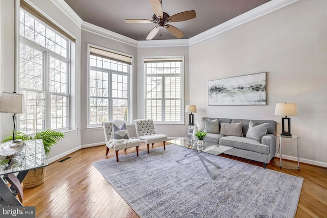 living room with ceiling fan, plenty of natural light, and crown molding