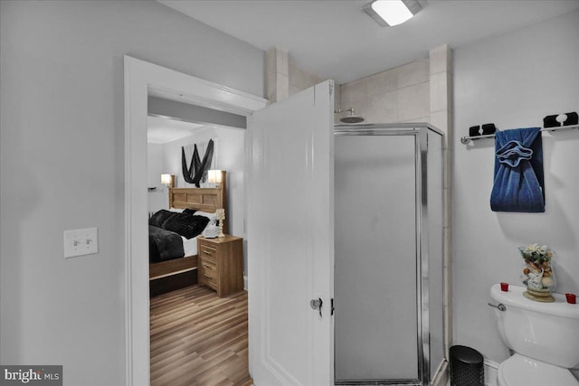 bathroom featuring toilet, hardwood / wood-style floors, and a shower with shower door