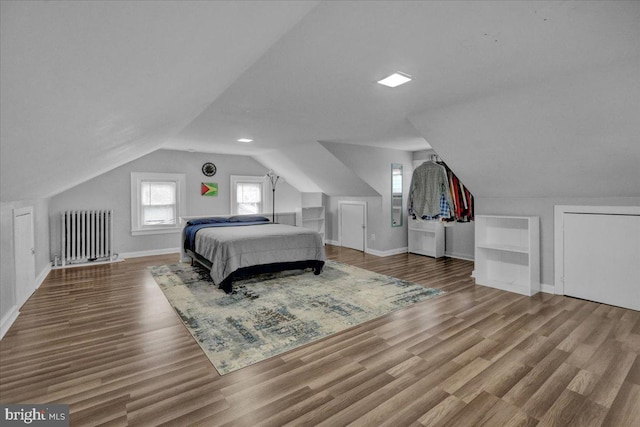 bedroom with hardwood / wood-style flooring, lofted ceiling, and radiator