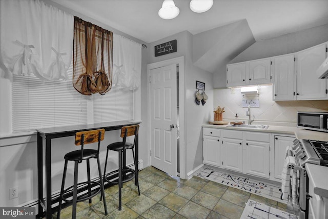 kitchen featuring sink, decorative backsplash, stainless steel appliances, and white cabinets