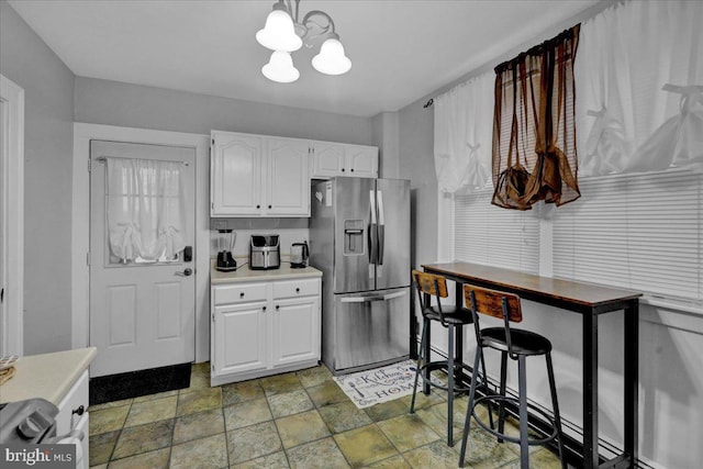 kitchen featuring hanging light fixtures, white cabinetry, stainless steel fridge, and an inviting chandelier