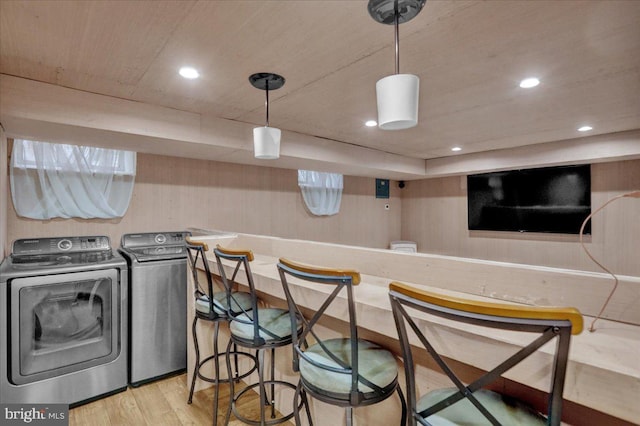 interior space with bar area, wooden walls, and light wood-type flooring