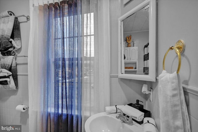 bathroom with tile walls, sink, and crown molding