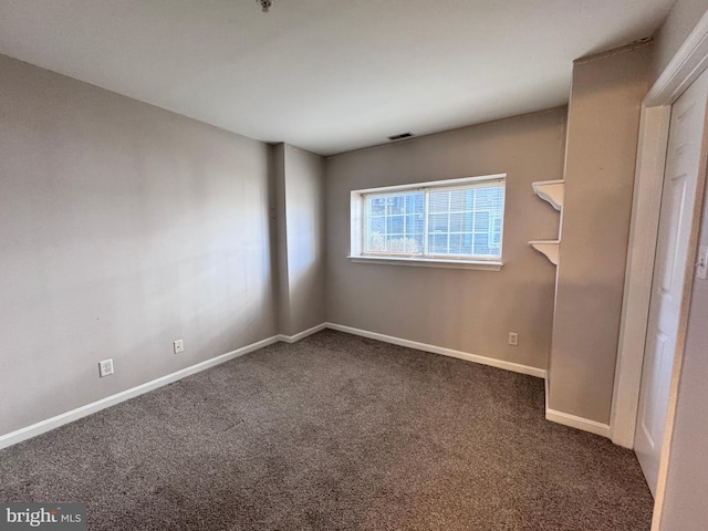 spare room featuring dark carpet
