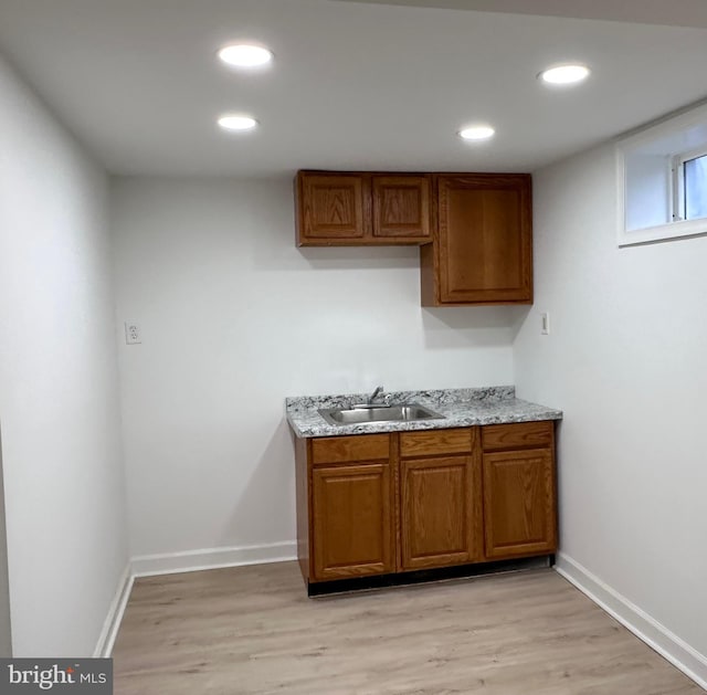 kitchen with light stone countertops, sink, and light hardwood / wood-style flooring