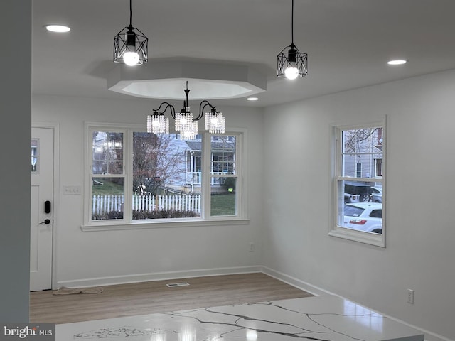 unfurnished dining area with a chandelier, light wood-type flooring, and a healthy amount of sunlight