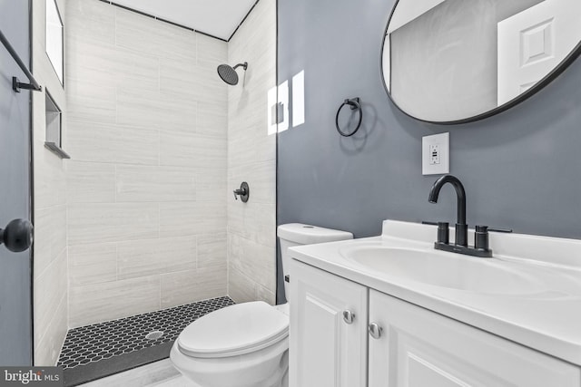 bathroom featuring vanity, toilet, and tiled shower