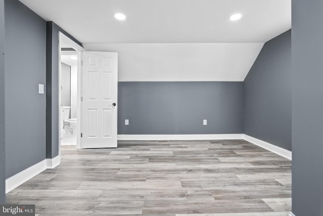 additional living space with light hardwood / wood-style floors and lofted ceiling