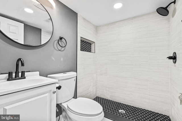 bathroom featuring tiled shower, vanity, and toilet