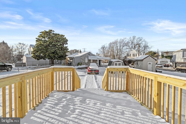 snow covered deck featuring a storage shed