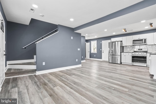 kitchen featuring white cabinets, light hardwood / wood-style flooring, stainless steel appliances, and tasteful backsplash