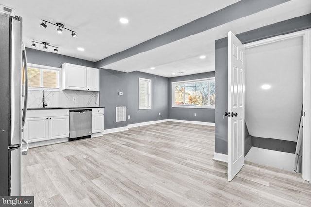 kitchen with sink, light hardwood / wood-style flooring, appliances with stainless steel finishes, tasteful backsplash, and white cabinetry