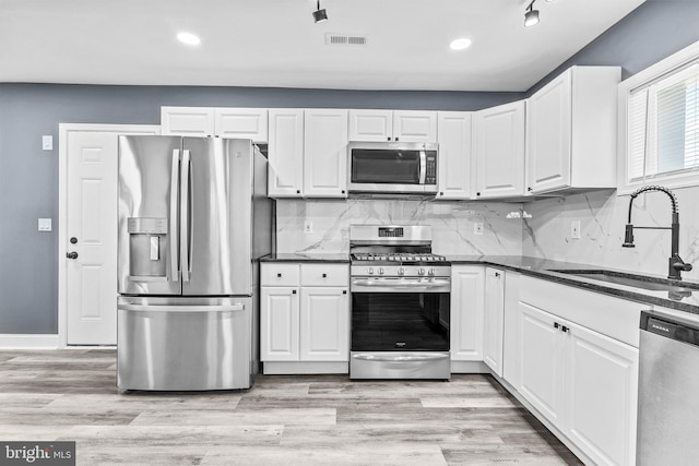 kitchen with white cabinetry, sink, light hardwood / wood-style flooring, and appliances with stainless steel finishes