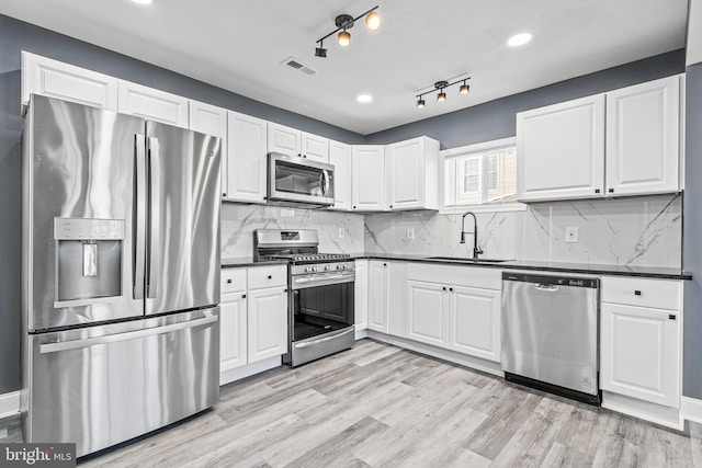 kitchen with white cabinets, light hardwood / wood-style floors, sink, and appliances with stainless steel finishes